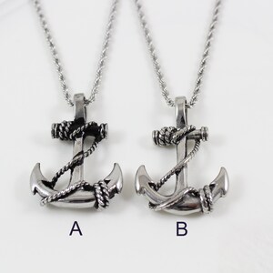 May include: Two silver anchor necklaces with black rope detail. The anchors are identical except for the rope detail, which is slightly different on each necklace. The necklaces are on a white background.