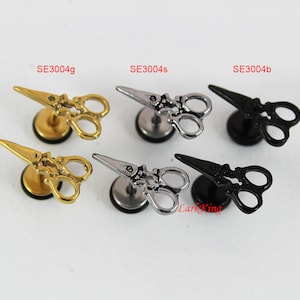 May include: Three pairs of earrings featuring a pair of scissors design. The earrings are available in gold, silver, and black.