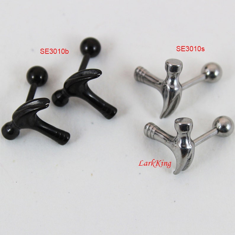May include: Two pairs of hammer-shaped barbell earrings. One pair is black and the other is silver.
