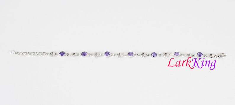 May include: A silver bracelet with a chain link design and purple gemstones. Lark King is printed in red on the bottom right corner of the image.