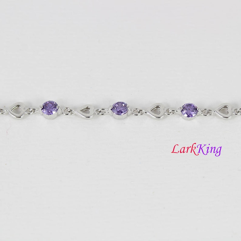 May include: A silver bracelet with a heart-shaped design and purple gemstones.