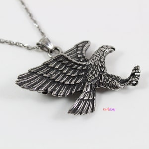 May include: Silver eagle pendant necklace with a detailed design. The eagle is in flight with its wings spread wide. The necklace is made of stainless steel.