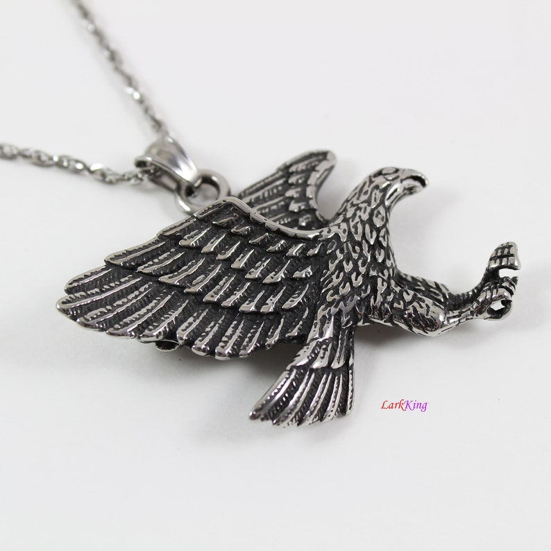 May include: Silver eagle pendant necklace with a detailed design. The eagle is in flight with its wings spread wide. The necklace is made of stainless steel.