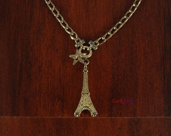 May include: A gold chain necklace with a charm of the Eiffel Tower and a star. The chain is a curb style.