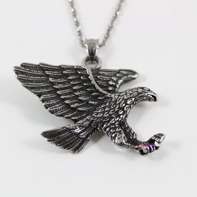 May include: Silver toned eagle pendant necklace. The eagle is in flight with its wings spread and talons extended. The necklace has a silver chain.