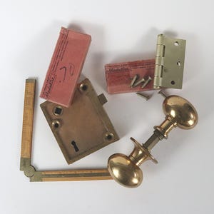 May include: A set of brass door hardware including a door knob, a door latch, a door hinge, and screws. The hardware is packaged in pink boxes labeled "Medallist".