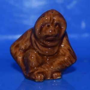 May include: A brown ceramic figurine of an orangutan sitting with its arms crossed. The figurine is detailed with a textured surface and a realistic expression.