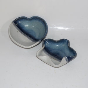 May include: Two ceramic heart-shaped bowls, one with a blue and white glaze and the other with a blue and white glaze with a wavy edge.