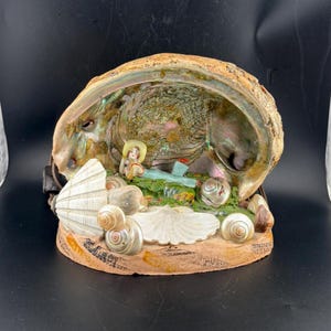 May include: A set of three ceramic mugs with a speckled, matte finish. The mugs are in shades of cream, light gray, and dark gray. Each mug has a simple, minimalist design and a rounded handle.