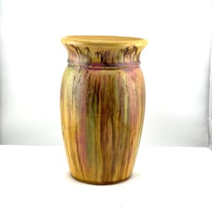 May include: A tall, ceramic vase with a wide, slightly flared rim. The vase features vertical stripes of yellow, green, and pink hues. The exterior has a textured, aged appearance, suggesting a vintage or handcrafted origin.