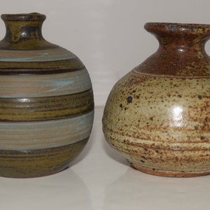 May include: Two ceramic vases, one with brown, green, and blue stripes and the other with brown and beige speckles.