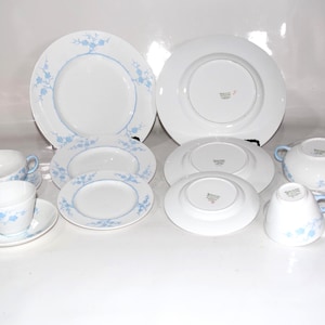Pu&ograve; includere: Una collezione di stoviglie in porcellana bianca con un motivo floreale azzurro. Il set comprende piatti di varie dimensioni, zuppiere, tazze e piattini. I piatti e le ciotole hanno un bordo floreale blu.