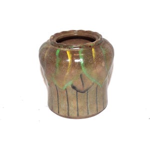 May include: A ceramic pot with a brown glazed finish and a crackled texture. The upper section features a scalloped rim and decorative petal-like patterns in shades of green and yellow. The lower body has vertical lines etched into the surface.