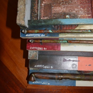 May include: Close-up of a stack of wooden boards with copper pipes and the text "CARUBIA VERA 90" and "CARUBIA VERA 91" written on them.