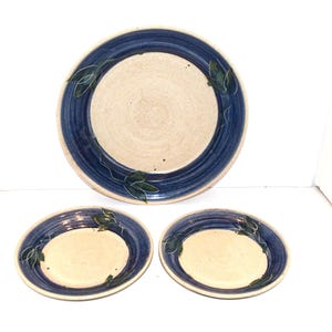 May include: A white ceramic mug with a black handle and the text "But First, Coffee" in a bold, black font. The mug is set against a blurred background, highlighting its clean design.