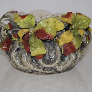 May include: A ceramic planter with a gray and white base and a vine design. The vine is decorated with green, yellow, and red leaves.