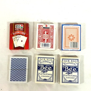 Puede incluir: Vista cenital de seis barajas de cartas. Las barajas son de varios colores y dise&ntilde;os, incluyendo rojo, azul y blanco. Algunas barajas est&aacute;n etiquetadas como "Stop Shop" y "Bee".