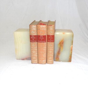 May include: Three hardcover books titled The Poems of Browning, The Works of Shakespeare, and The Poems of Longfellow, positioned between two rectangular, translucent, cream and orange-veined stone bookends with smooth, polished surfaces.