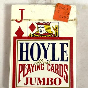 Puede incluir: Una baraja de cartas Hoyle Official, tama&ntilde;o Jumbo, en una caja blanca y roja. La caja presenta una ilustraci&oacute;n de la jota de diamantes y el logotipo de Hoyle en azul y rojo. Una etiqueta de precio naranja est&aacute; adjunta.