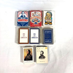 Puede incluir: Una colecci&oacute;n de barajas de cartas pol&iacute;ticas vintage. Las barajas presentan im&aacute;genes de pol&iacute;ticos y el texto "Bush Cards", "Politicards" y "Win with Lowenstein". Las barajas son de varios colores y dise&ntilde;os.