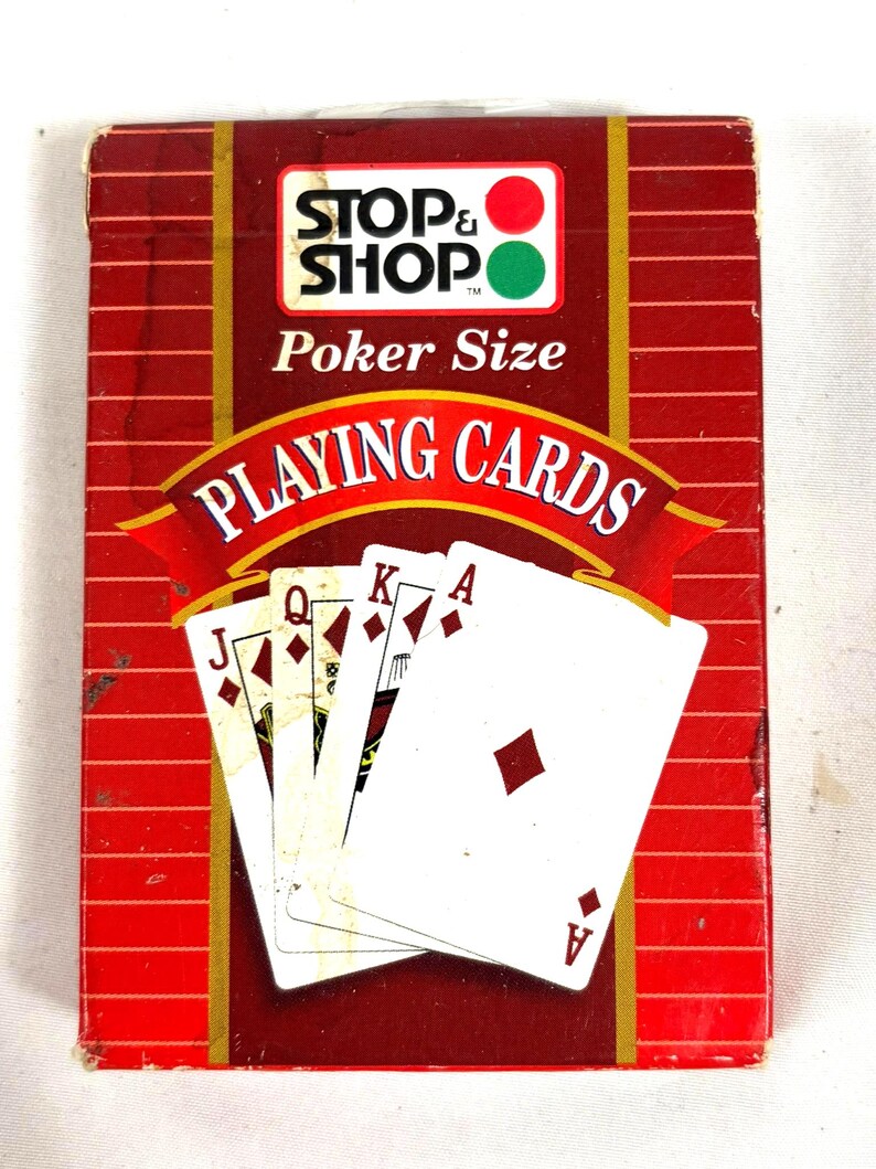 Puede incluir: Una baraja de cartas de p&oacute;quer de la marca "Stop & Shop". La caja roja y blanca presenta el logotipo de Stop & Shop y las palabras "Poker Size" y "Playing Cards". Las cartas est&aacute;n abanicadas, mostrando el As de diamantes y otras figuras.