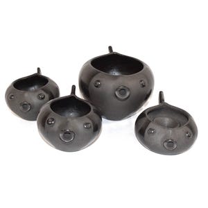May include: Four dark gray ceramic bowls with a unique design. Each bowl has a rounded shape with a small handle and circular indentations, resembling a face. The bowls vary in size and are arranged on a white background.