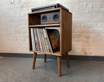 Könnte beinhalten: Ein Holzständer für einen Plattenspieler mit einem Regal für Schallplatten und einem Lautsprechersystem oben. Der Ständer hat vier Beine und ist aus dunkelbraunem Holz.