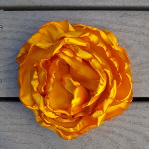 May include: A large, bright yellow silk flower with multiple layers of petals.