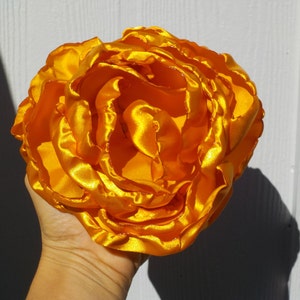 May include: A large, bright yellow satin flower with multiple layers of petals.