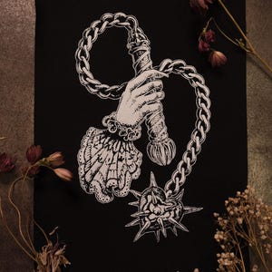 Peut inclure: Illustration en noir et blanc d'une main tenant un fléau, avec une chaîne et des éléments décoratifs. Le design présente des détails complexes et une esthétique gothique, adapté aux écussons ou aux impressions.