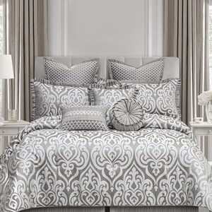 May include: A gray and white damask patterned bedding set with a variety of decorative pillows. The set includes a comforter, bed skirt, and several throw pillows.