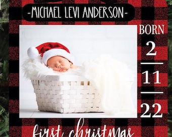 May include: A red and black buffalo plaid Christmas ornament with a photo of a baby in a white basket. The ornament says "Michael Levi Anderson - Born 2-11-22 - First Christmas".