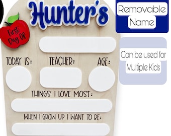 May include: A wooden first day of school sign with a red apple and the words "First Day Of" on it. The sign has blank spaces for the child's name, teacher, age, things they love most, and what they want to be when they grow up. The sign also has a removable name tag.