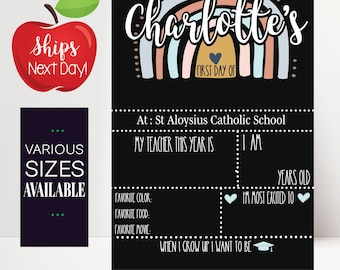 May include: A black chalkboard with a rainbow design and the text "Charlotte's First Day Of". The chalkboard has spaces to fill in information about the child's first day of school, including their teacher, age, and what they are most excited for.