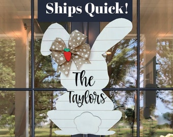 May include: White wooden bunny door hanger with a brown and white polka dot bow and a red strawberry. The bunny has the text "The Taylors" written on it. The sign also has the text "Ships Quick!" on it.