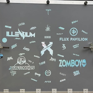 K&ouml;nnte beinhalten: Eine graue Oberfl&auml;che mit verschiedenen Logos und Texten in Hellblau. Zu den Logos geh&ouml;ren "ILLESIUM", "SUBTRONICS", "ZOMBOY" und "FLUX PAVILION". Auch K&uuml;nstlernamen und Event-Branding sind zu sehen.