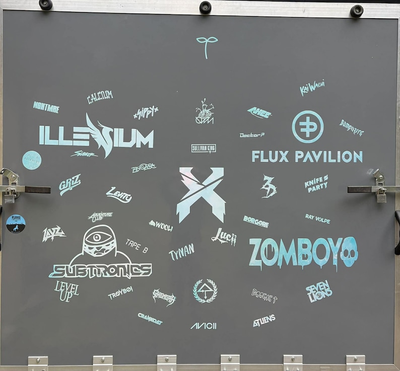 K&ouml;nnte beinhalten: Eine graue Oberfl&auml;che mit verschiedenen Logos und Texten in Hellblau. Zu den Logos geh&ouml;ren "ILLESIUM", "SUBTRONICS", "ZOMBOY" und "FLUX PAVILION". Auch K&uuml;nstlernamen und Event-Branding sind zu sehen.