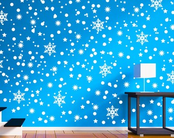 May include: A bright blue wall decorated with numerous white snowflake and star decals of varying sizes. The wall is positioned behind a staircase with white risers and dark treads, and a dark table with a white lamp sits to the right side.