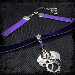 May include: A purple velvet choker necklace with a silver dragon pendant and a purple amethyst bead. The necklace has a silver chain extender.