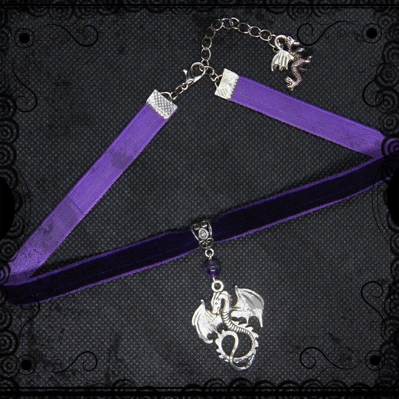May include: A purple velvet choker necklace with a silver dragon pendant and a smaller silver dragon charm on a silver chain.