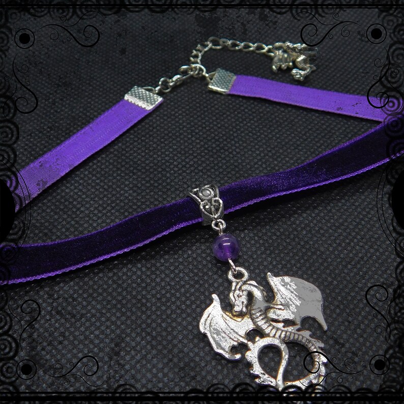 May include: A purple velvet choker necklace with a silver dragon pendant and a purple amethyst bead. The necklace has a silver chain and clasp.