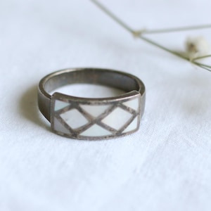 Elegant pärlring med ett fint metallkors på en bred pärlplatta.
