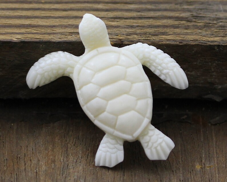 Hand carved buffalo bone sea turtle pendant, approx. 40mm, featuring detailed flippers and shell design. A symbolic ocean totem representing wisdom, longevity, and protection, perfect for jewelry making, spiritual crafts, or as a unique artisan carving.