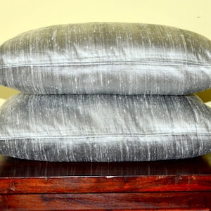 May include: Two silver pillow covers with a subtle shimmer. The pillow covers are made of a soft, luxurious fabric and are perfect for adding a touch of elegance to any room.