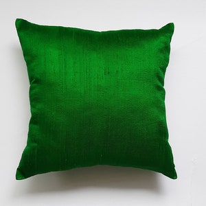 May include: A solid green square pillow made of a soft, silky fabric.