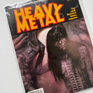 May include: Cover of Heavy Metal magazine, December 1981, featuring an illustration of a woman with long black hair and a metallic body, standing in front of a dark, textured background. The cover story is "Deborah Harry meets Alien artist H.R. Giger".