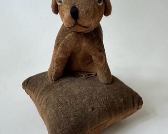 Perro de peluche antiguo hecho a mano con saco de pienso sobre un cojín