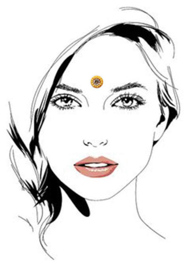 Op de afbeelding: Een zwart-witte lijntekening van een vrouwen gezicht met een gouden en witte bindi op haar voorhoofd.