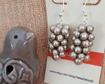 May include: A pair of dangle earrings with silver hooks and a cluster of grey pearl-like beads. The earrings are displayed on a white card with the text "www.etsy.com/shop/beauteousb".