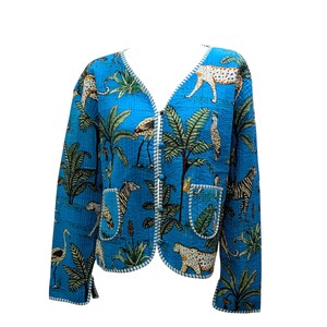 May include: A blue quilted jacket with a white trim and a safari animal print. The jacket has a V-neck and a button closure.